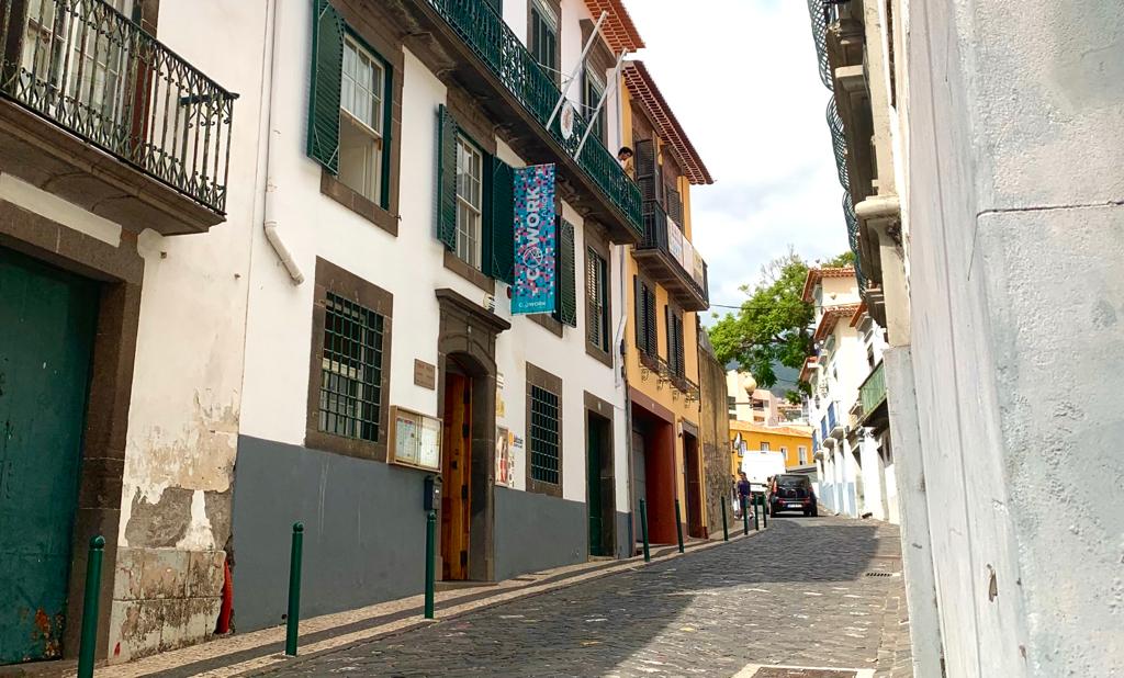 A historical Funchal street with clapboard windows and parking posts painted green