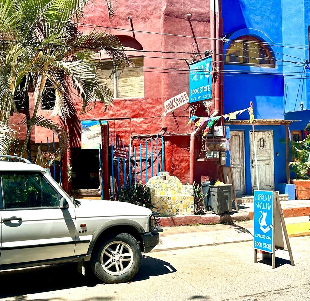 Exterior blue and red of bookstore in Sayulita with sign saying "Libreria Sayulita - BOOKSTORE"