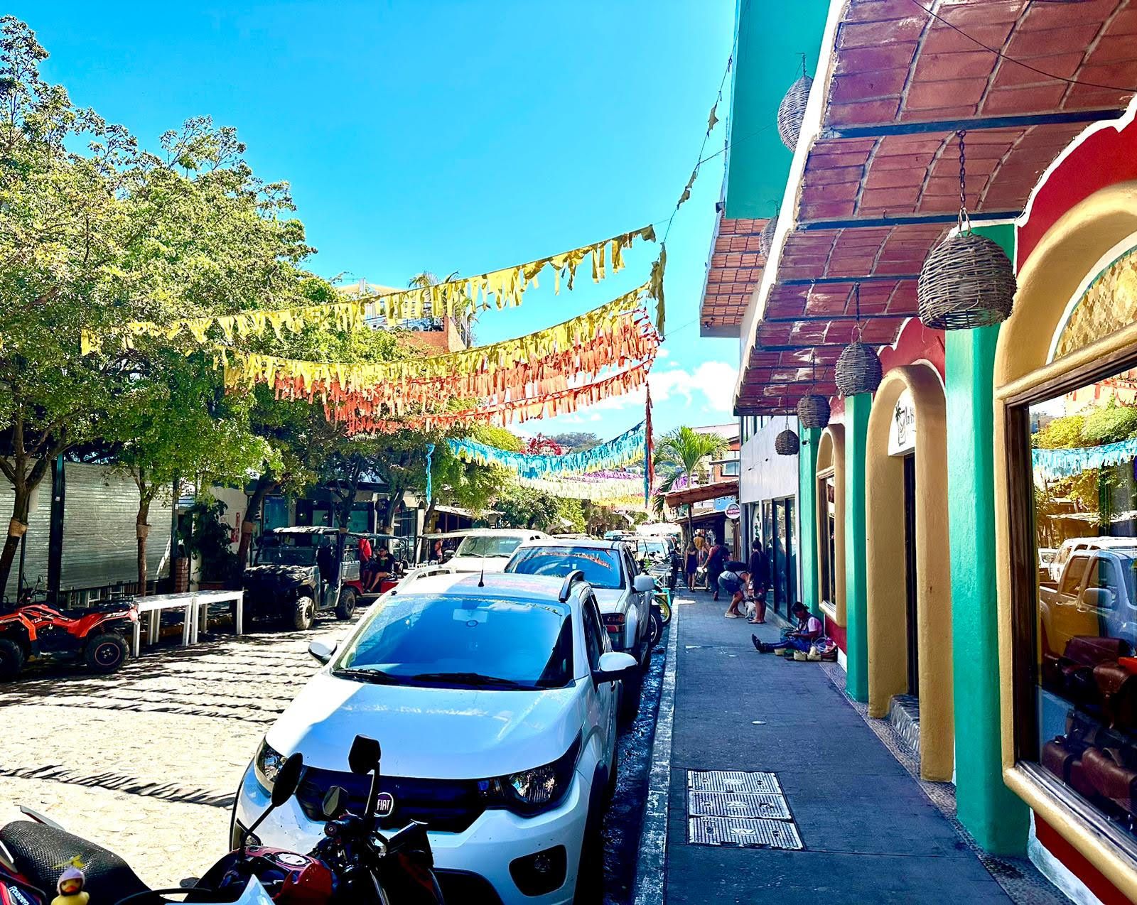 The streets of Sayulita, Mexico with banners, colourful buildings and cars