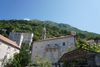 A mountain overlooks a Montenegrin village with a view of the blue sky