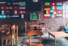 Flags of the world and a clock shaped like a soccer field in a room with brick walls and wooden furniture