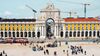 An archway in Lisbon backgrounded by cranes and foregrounded by streetcars and tourists