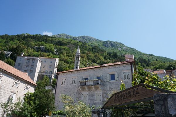 A mountain overlooks a Montenegrin village with a view of the blue sky